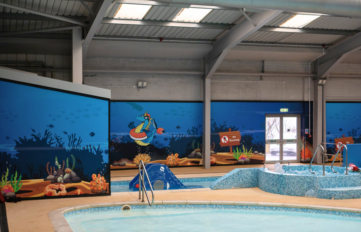 A children's splash zone within a heated indoor swimming pool complex