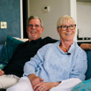 A couple sat smiling together on a sofa