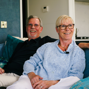 A couple sat smiling together on a sofa