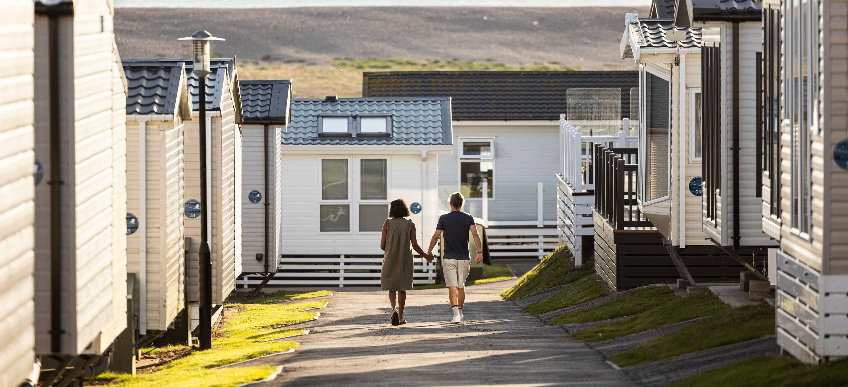 Couple walking down lane between caravans
