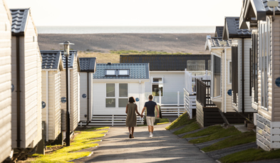 Couple walking down lane between caravans