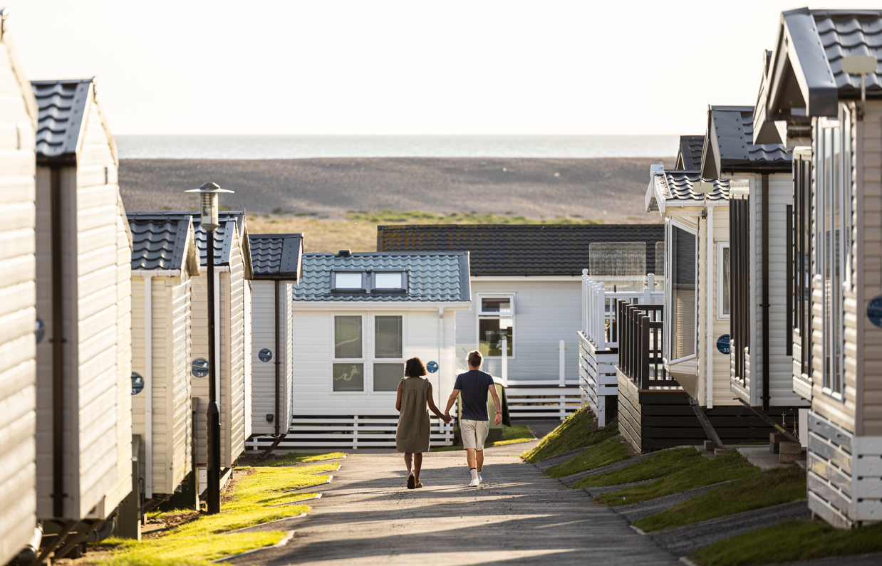 Couple walking down lane between caravans