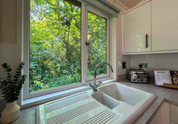 Internal of a lodge kitchen sink with views out to woodland 