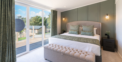 Beautifully designed Master bedroom showcasing king-size bed, comfy ottoman, and floor-to-ceiling sliding doors out onto the large balcony