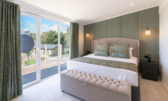 Beautifully designed Master bedroom showcasing king-size bed, comfy ottoman, and floor-to-ceiling sliding doors out onto the large balcony