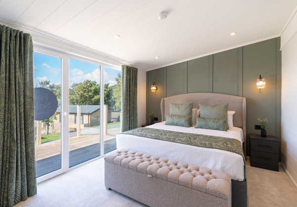 Beautifully designed Master bedroom showcasing king-size bed, comfy ottoman, and floor-to-ceiling sliding doors out onto the large balcony