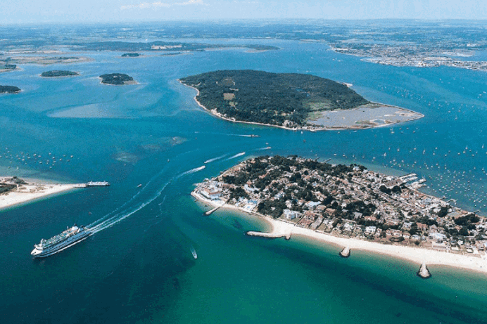 An aerial view of the coast with various islands and boats scattered in the striking blue water on a sunny day
