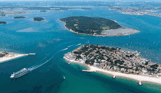 An aerial view of the coast with various islands and boats scattered in the striking blue water on a sunny day