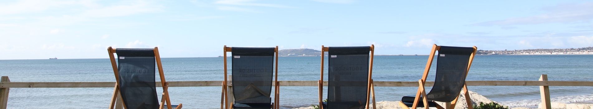 Deckchairs sat on the sand at Southside area overlooking the sea with blue skies