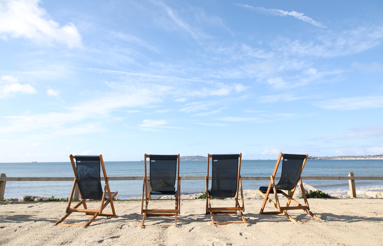 Deckchairs sat on the sand at Southside area overlooking the sea with blue skies