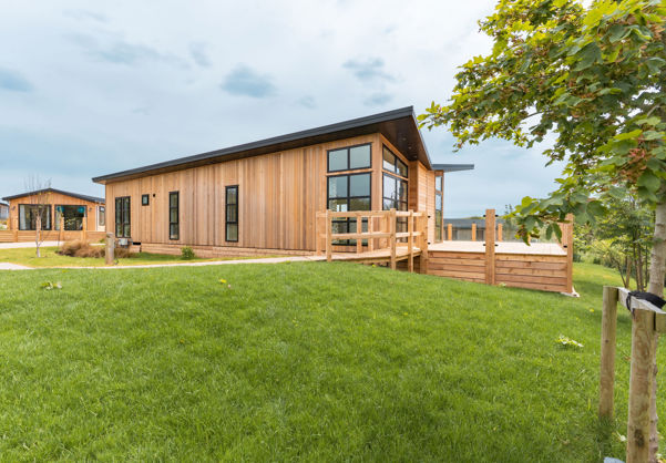 External of a luxury lodge on pitch with decking and surrounding green space