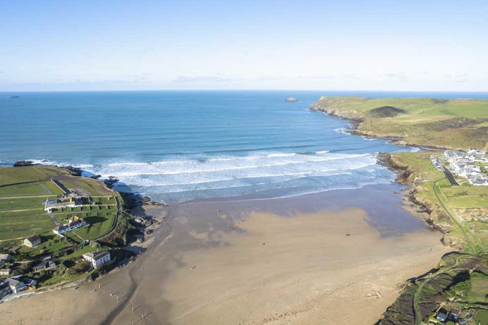 A sandy stretch of beach surrounded by countryside headland