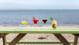 Four cocktails on an outdoor bench looking out to sea
