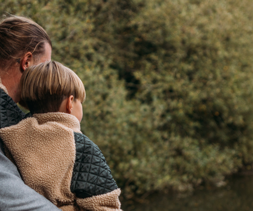 A family of three from behind among trees and lake