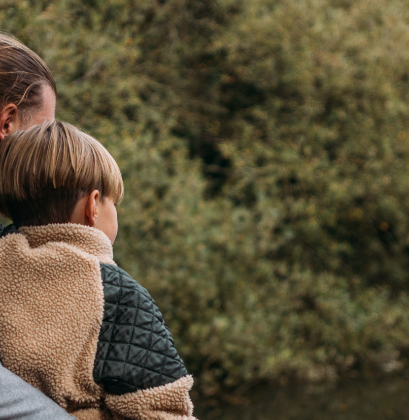 A family of three from behind among trees and lake