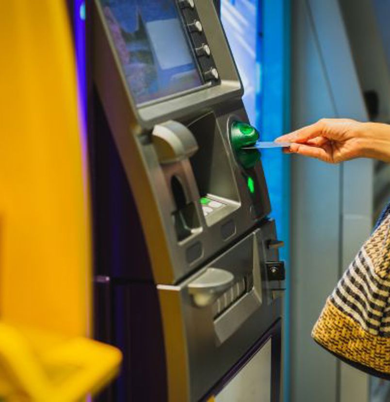 An image of someone inserting their bank card into an ATM to withdraw cash