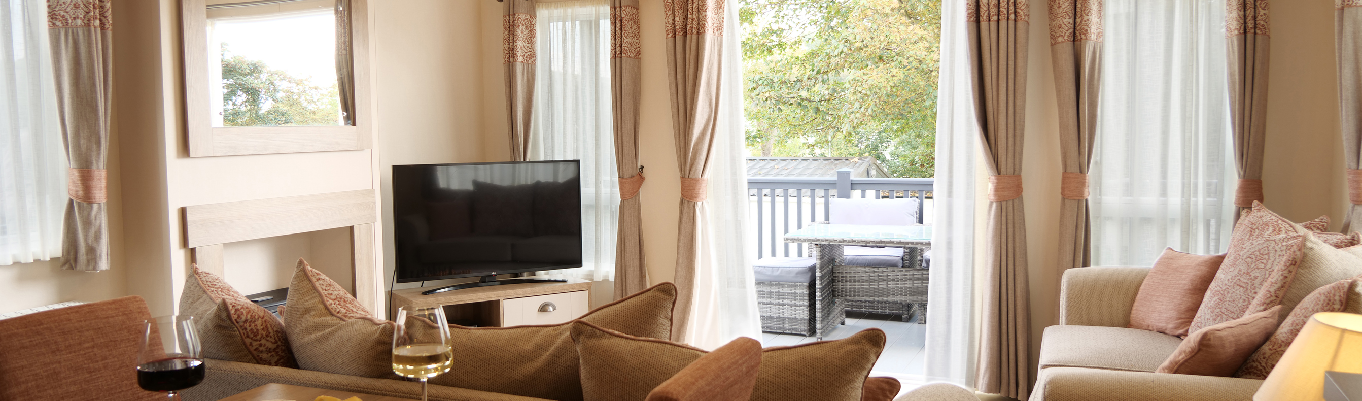 Lounge and Dining Area of a Caravan with French Doors Opening to Decking