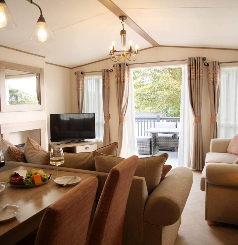 Lounge and Dining Area of a Caravan with French Doors Opening to Decking