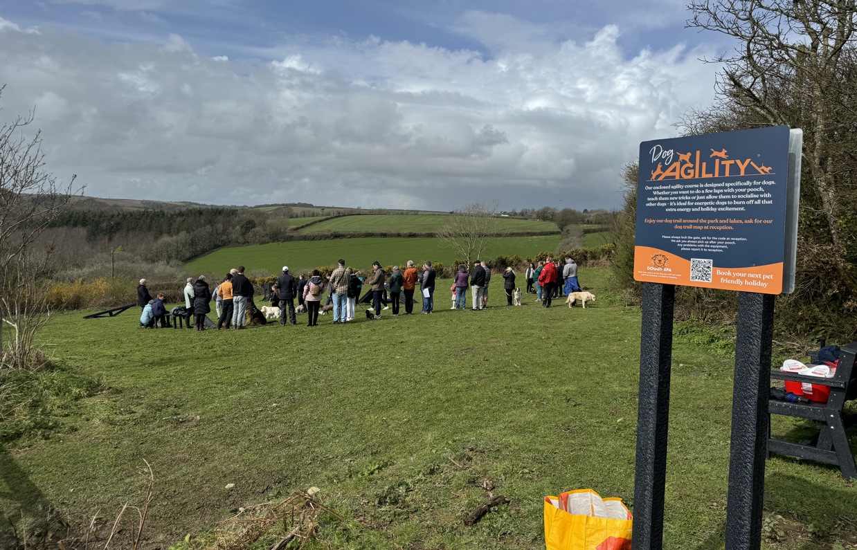 A group of people with dogs in a dog agility field for a Trufts Dog Show at Tregoad Holiday Park