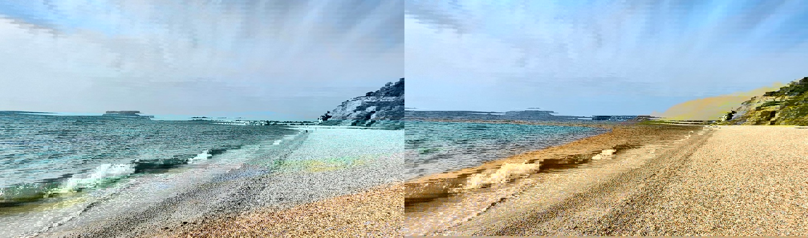 A shingle beach with calm sea and views of Portland and Weymouth Bay on a sunny blue sky day