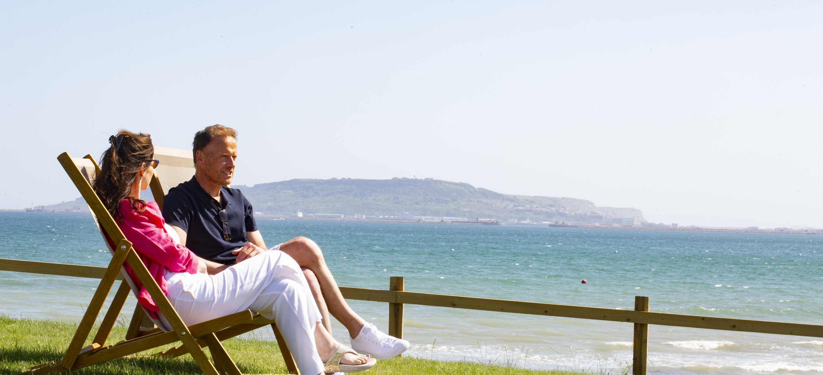 Couple relax on deckchairs overlooking Weymouth beach