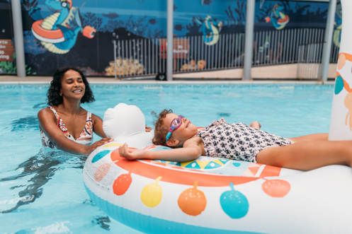A Mother and Daughter Playing in an Indoor Swimming Pool on an Inflatable