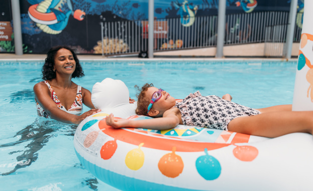 A Mother and Daughter Playing in an Indoor Swimming Pool on an Inflatable