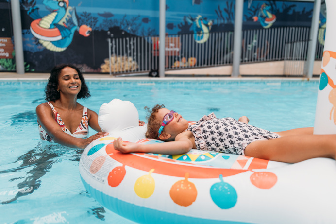 A Mother and Daughter Playing in an Indoor Swimming Pool on an Inflatable