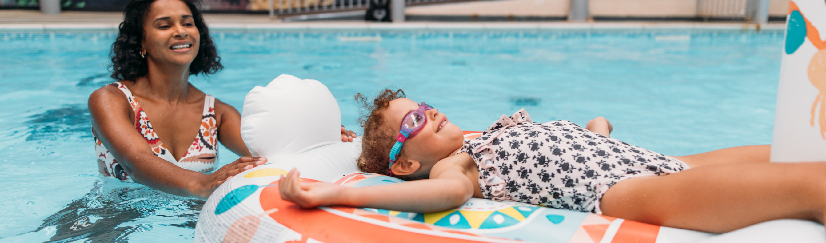 A Mother and Daughter Playing in an Indoor Swimming Pool on an Inflatable
