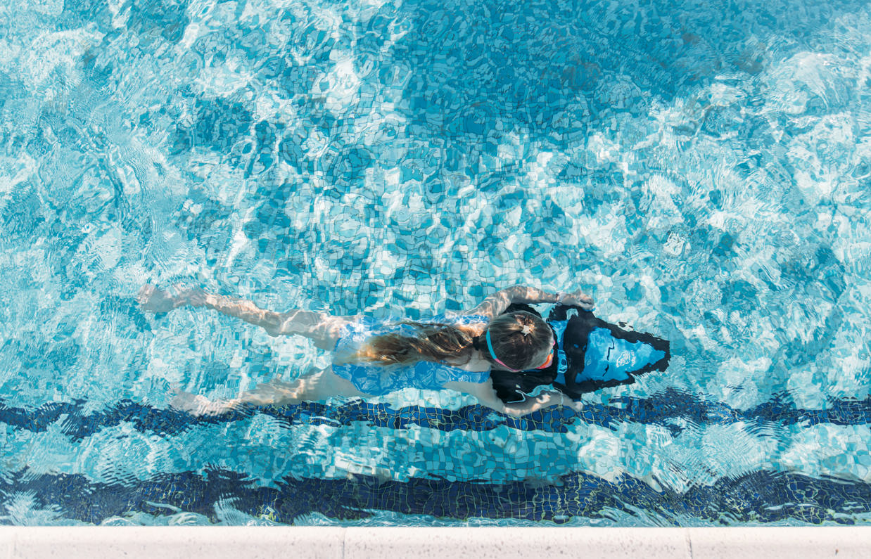 A young girl underwater in an outdoor pool on an aqua jet