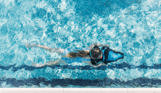 A young girl underwater in an outdoor pool on an aqua jet