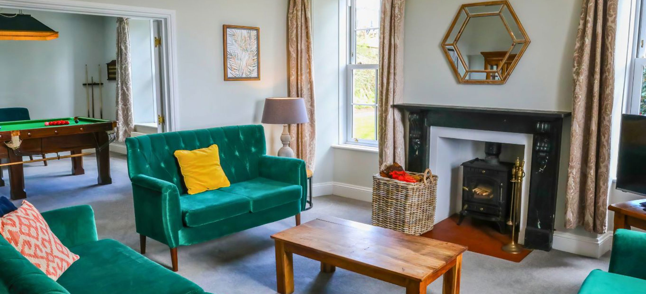 Internal of a manor house lounge with sofas and a tv leading on to the open snooker room