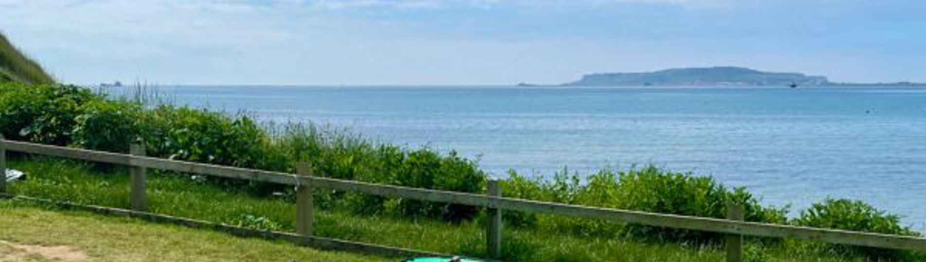 A range of kayaks sat in a field by the sea