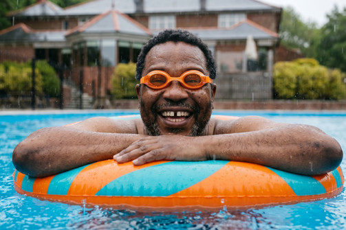 A happy man in a rubber ring in an outdoor pool