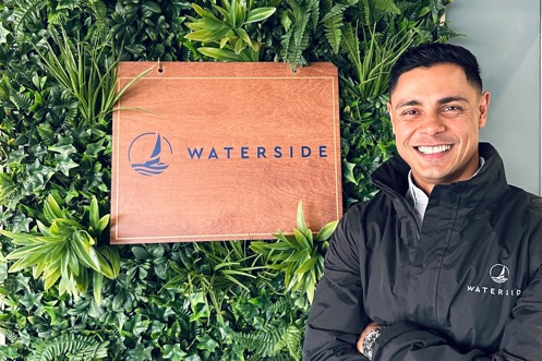 A smiling man stood beside a Waterside sign