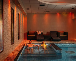 A Couple Relaxing in a Spa Pool with Loungers and Calm Lighting