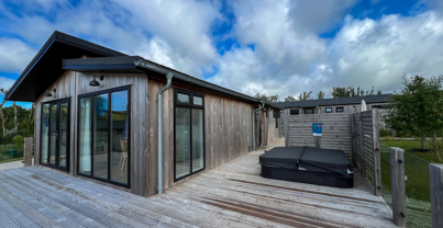 External of a luxury lodge on pitch with decking and hot tub
