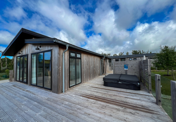 External of a luxury lodge on pitch with decking and hot tub