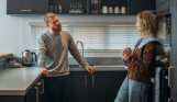 A couple standing in the kitchen of a luxury lodge at Tregoad Holiday Park smiling at each other