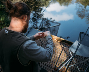 A man by the edge of a lake with fishing gear