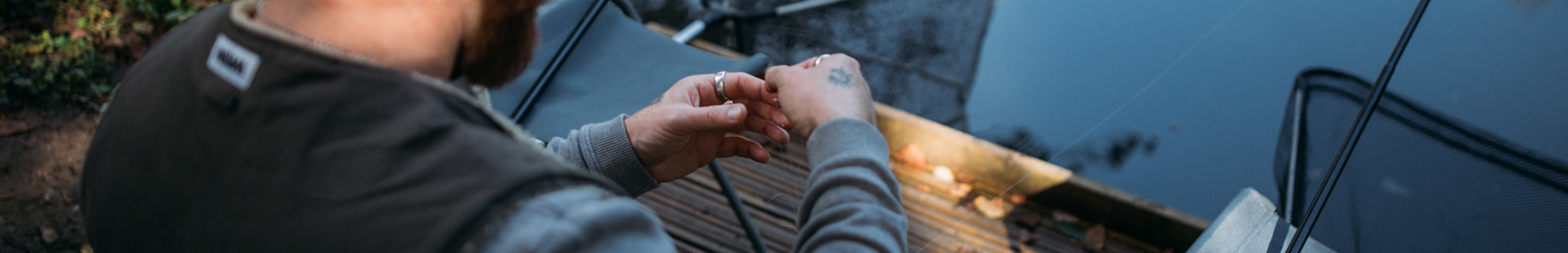 A man by the edge of a lake with fishing gear