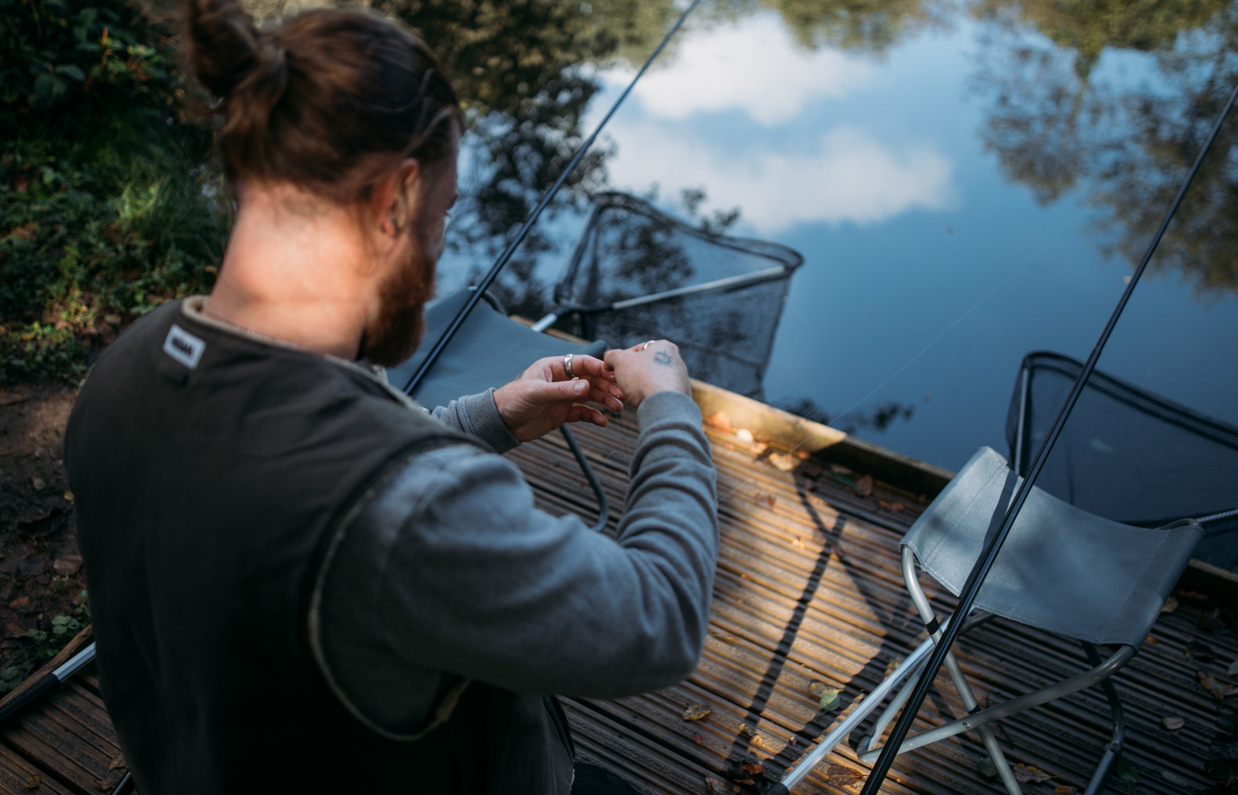 A man by the edge of a lake with fishing gear