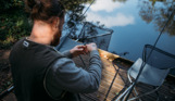 A man by the edge of a lake with fishing gear