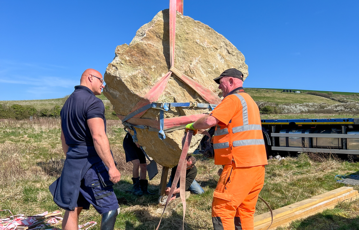 Installation of a stone sculpture in a field with blue skies
