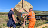 Installation of a stone sculpture in a field with blue skies