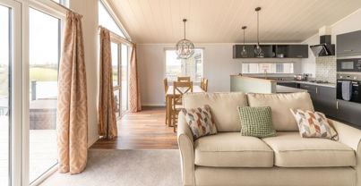 Open plan living area with sofa, dining area and kitchen and large windows and patio doors