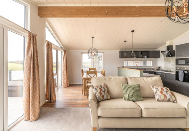 Open plan living area with sofa, dining area and kitchen and large windows and patio doors