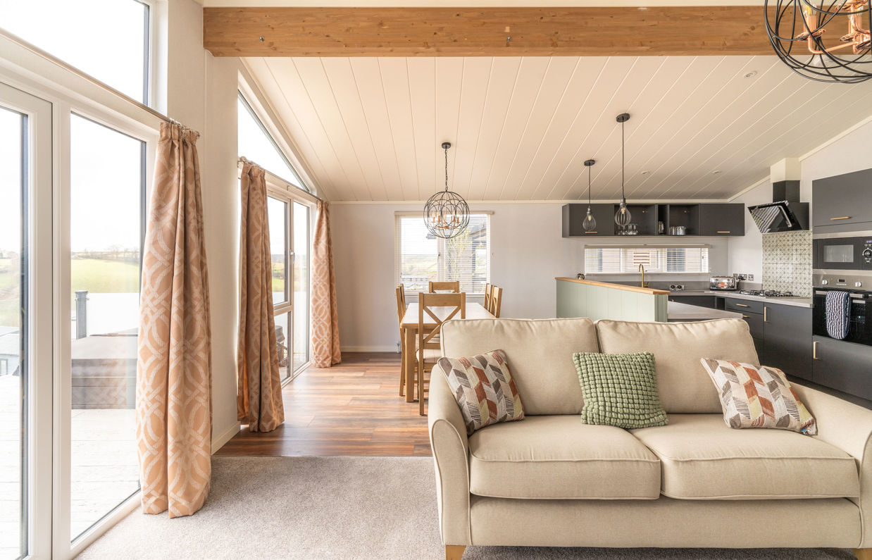 Open plan living area with sofa, dining area and kitchen and large windows and patio doors