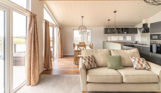 Open plan living area with sofa, dining area and kitchen and large windows and patio doors
