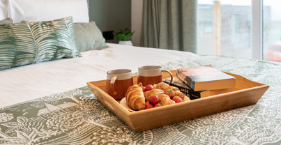 Bedroom focussing on comfy bed serenely decorated with breakfast-in-bed tray